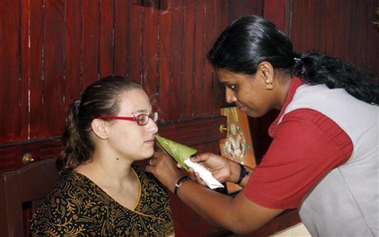 Sabine Steiger, 28, an anthropology student from Vienna, left, tries the "nasya" treatment at the Athreya Ayurvedic Resort in Kottayam, India. To perform this treatment, which is aimed at clearing the head, the therapist lights a cloth soaked in camphor and other substances, and the patient inhales the smoke. 